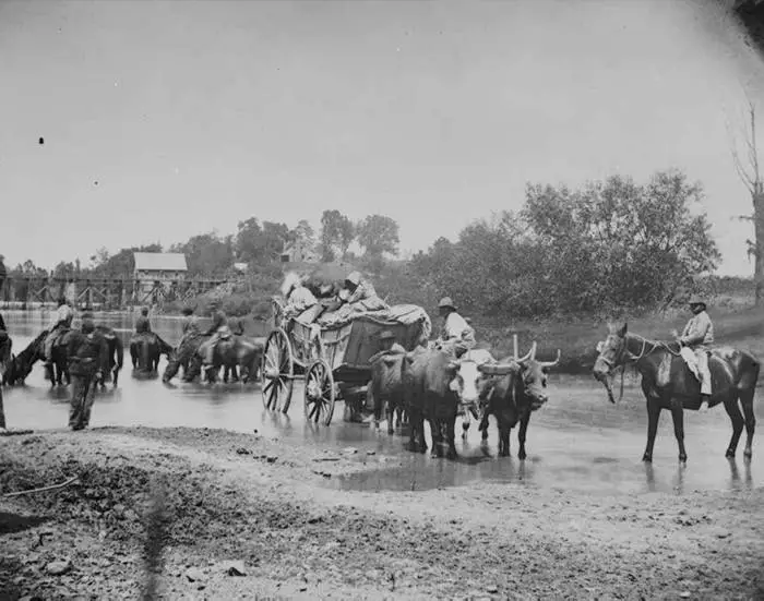 Runaway slaves crossing river in covered wagons